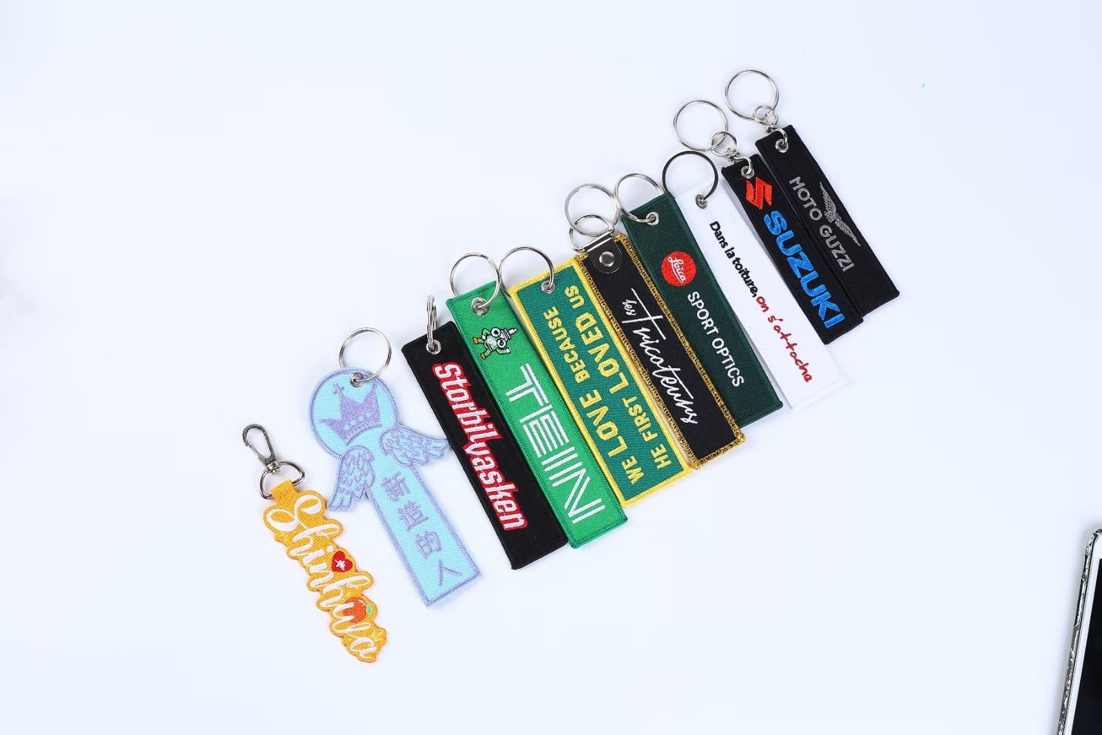 "Custom embroidered keychains with various logos and designs, including 'Schiebel' and 'Swobbee'."