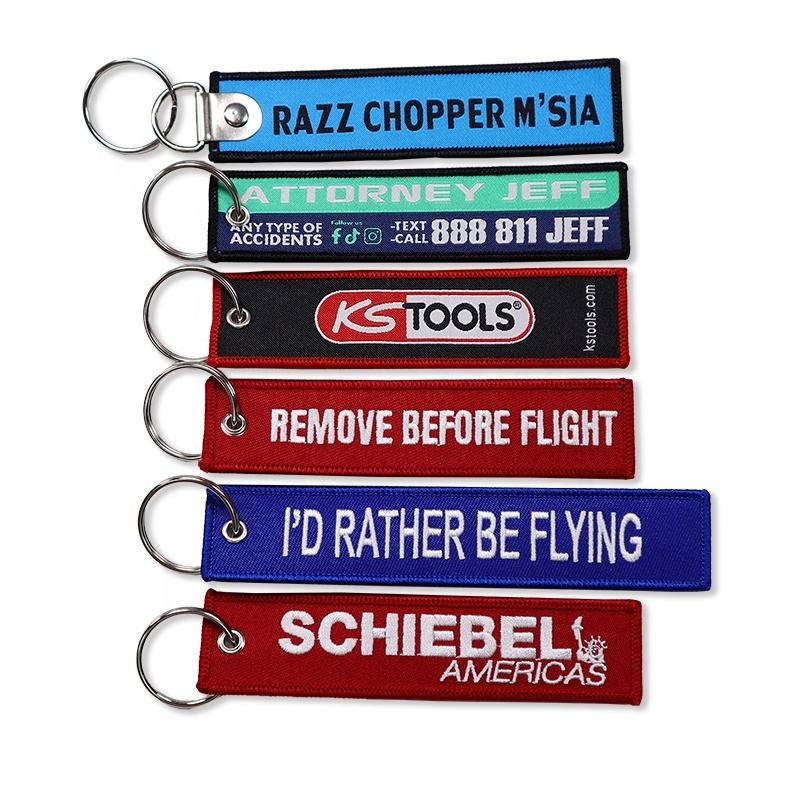 "Embroidered keychains with diverse branding such as 'Swobbee', 'KS Tools', and 'Remove Before Flight'."