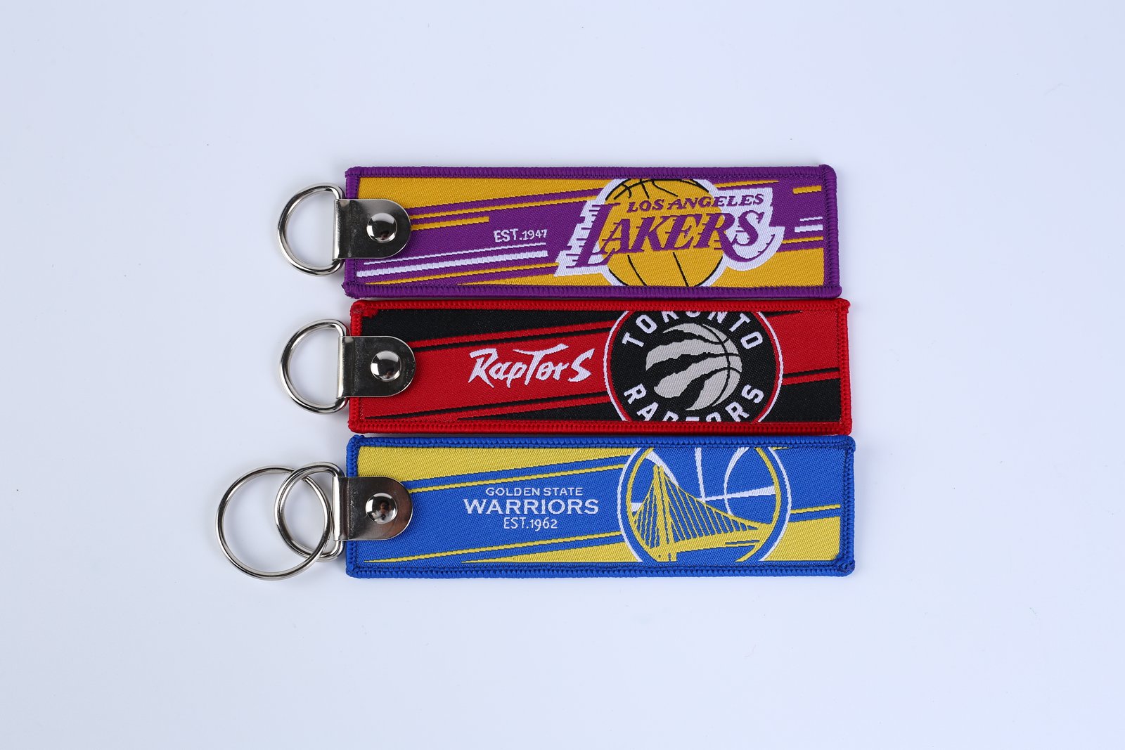 "Basketball team woven keychains with Lakers, Raptors, and Warriors logos"