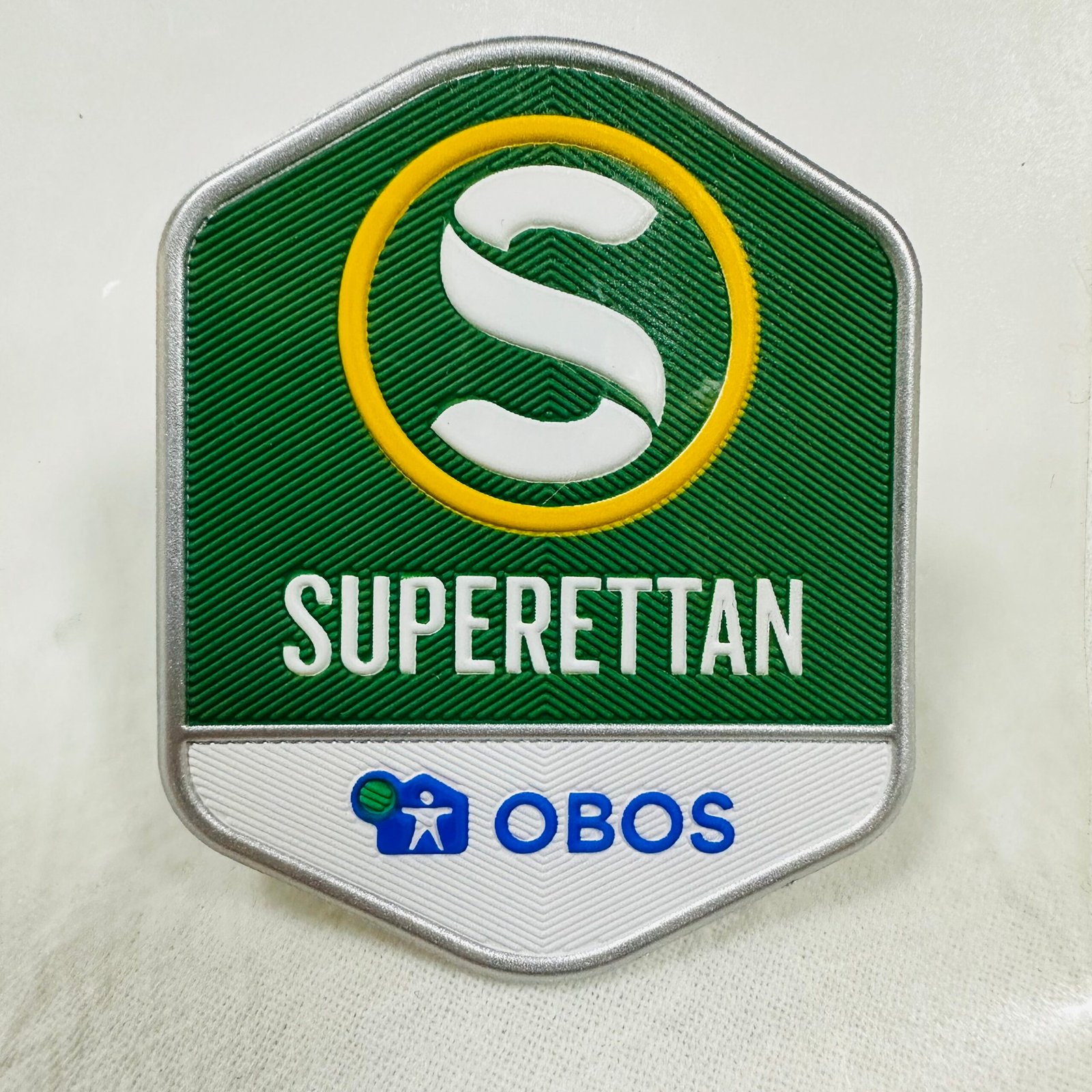 High-frequency embossed patch for Superettan team branding with green and white details.