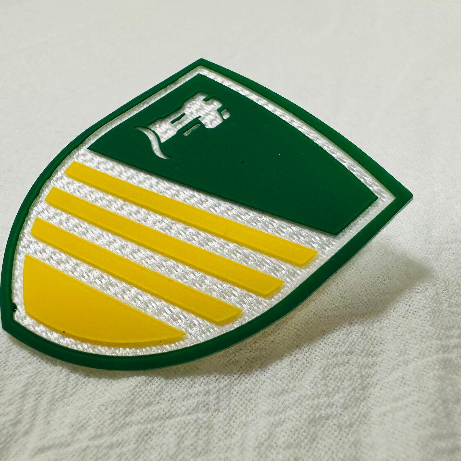 Custom Shield-Shaped High Frequency Embossed Patch with Green and Yellow Design.